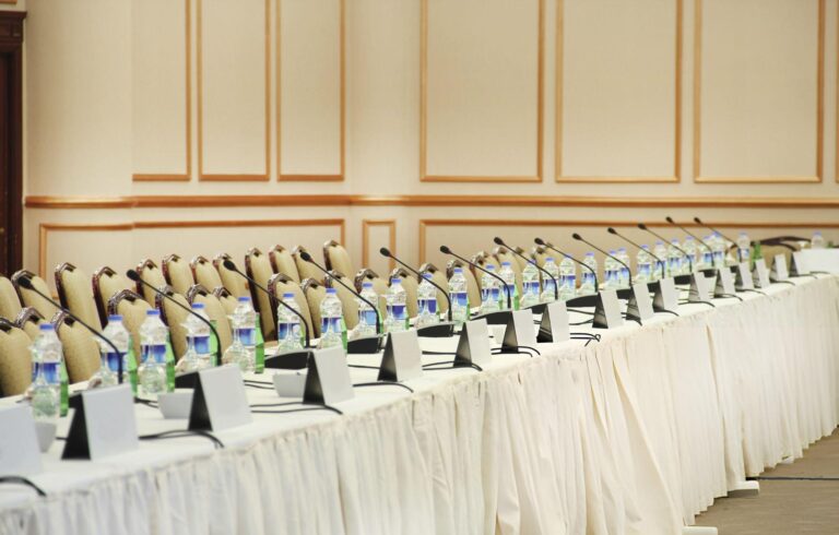 long table with microphones and water bottles for each seat